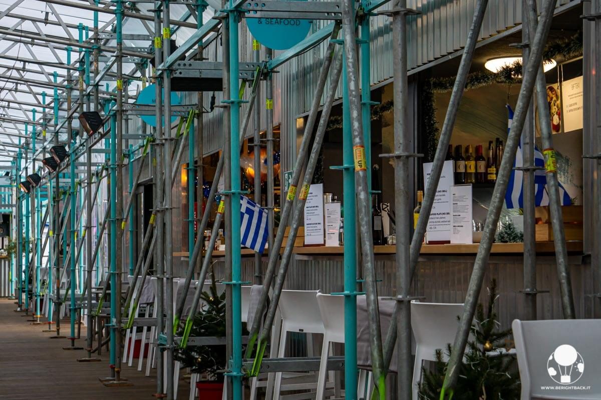 impalcature in ferro colorate e sedie bianche davanti agli stand