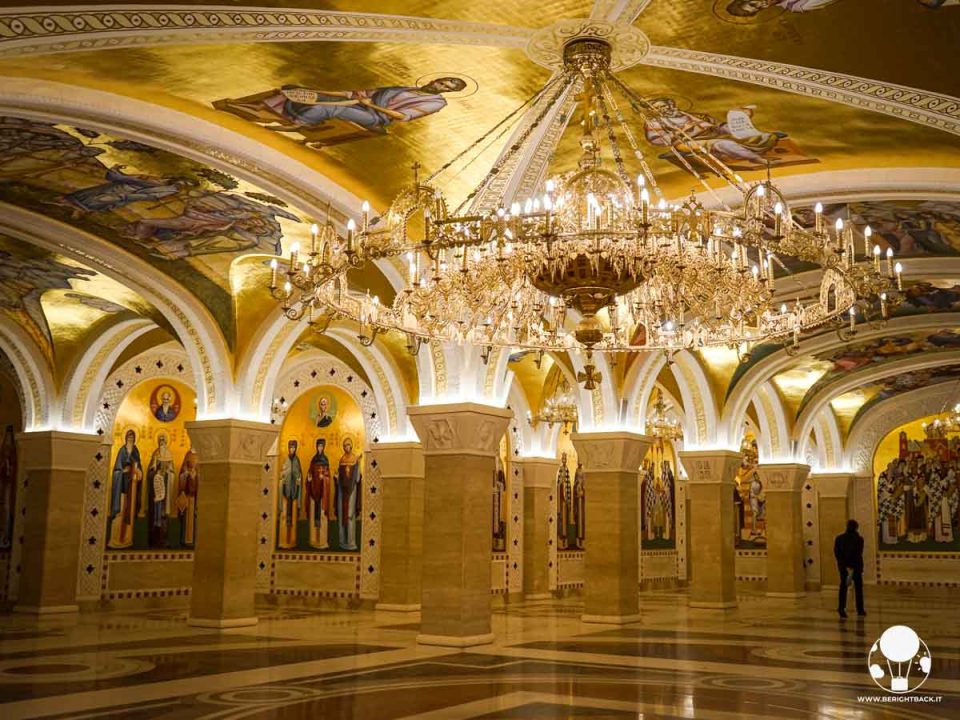 cripta di chiesa ortodossa con colonne, soffitti, pareti ed enorme lampadario dorati