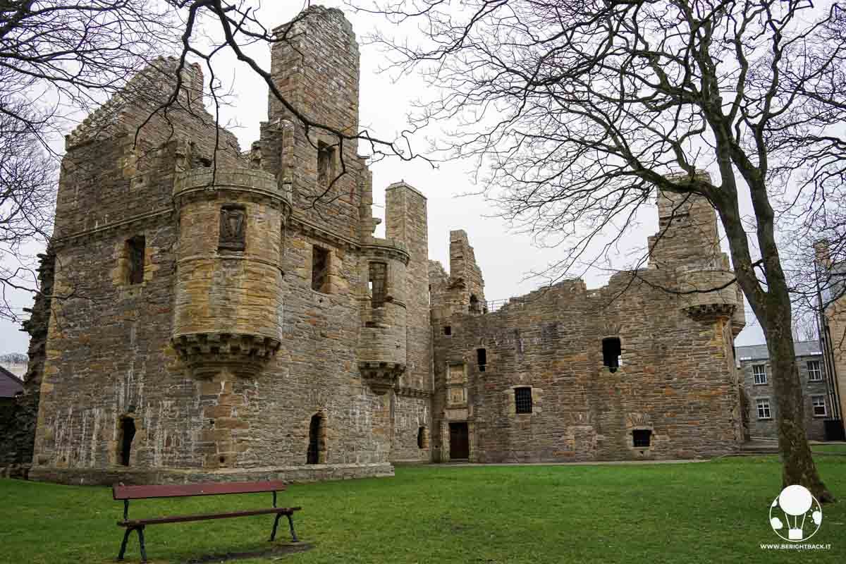 resti di un palazzo all'interno di un parco con una panchina in primo piano