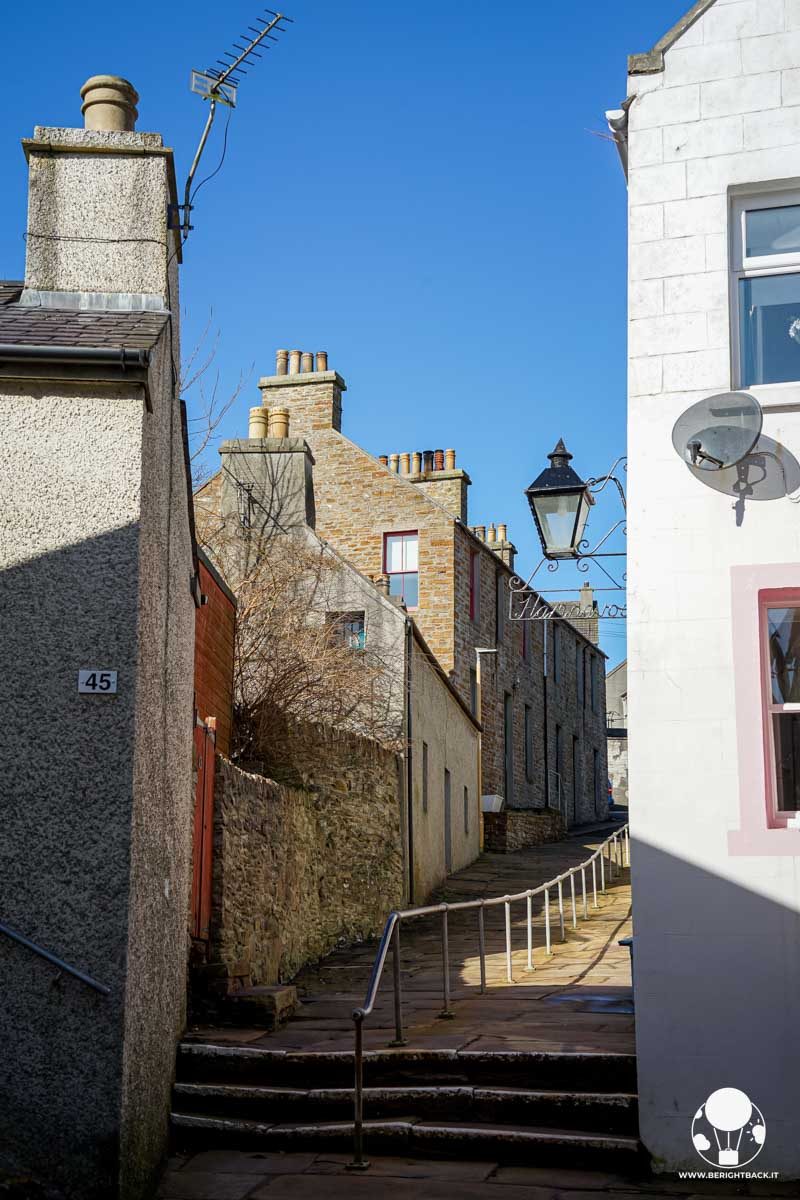 vicolo in salita con delle scale su cui si affacciano cottage con comignoli uguali